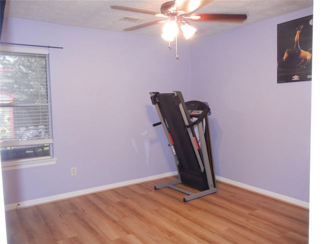 Secondary bedroom is spacious and has a walk-in closet, ceiling fan, and vinyl plank flooring. | Image 28