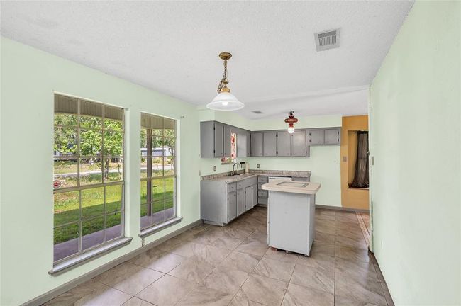 Bright and inviting dining area with large windows offering scenic views, seamlessly connected to a functional kitchen space. | Image 13