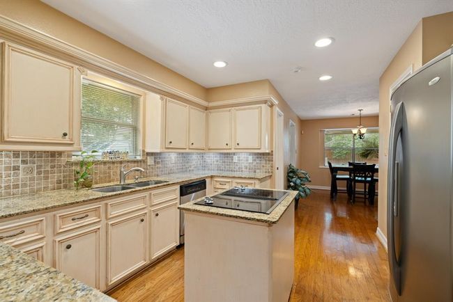 A beautiful tumbled stone backsplash and pristine granite counters make this kitchen a showplace! | Image 16