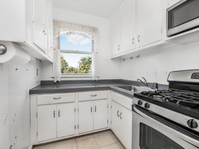 Kitchen featuring sink, appliances with stainless steel finishes, white cabinetry, and light tile patterned flooring | Image 8