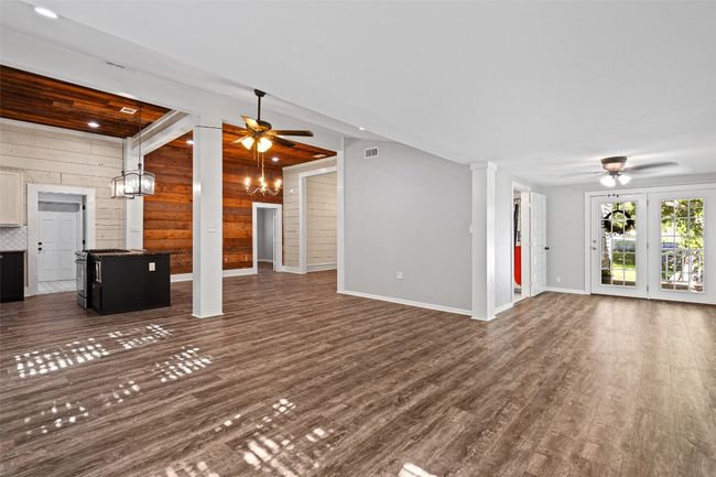 Unfurnished living room with ceiling fan, wood walls, dark wood-type flooring, and baseboards | Image 31