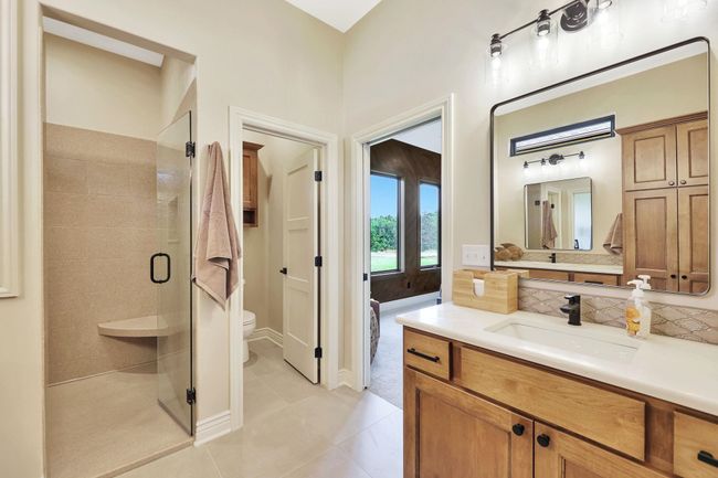 Bathroom with vanity, tasteful backsplash, a shower with shower door, tile patterned floors, and toilet | Image 24