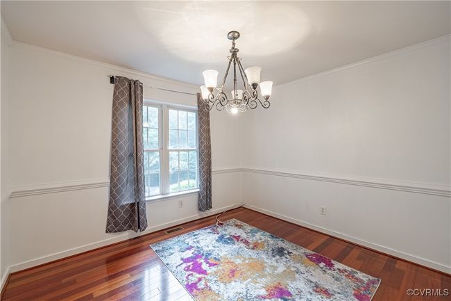 Spare room with a chandelier, wood finished floors, and crown molding | Image 6