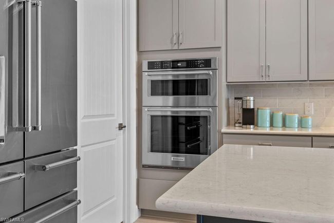 Kitchen with decorative backsplash, appliances with stainless steel finishes, and light stone countertops | Image 31