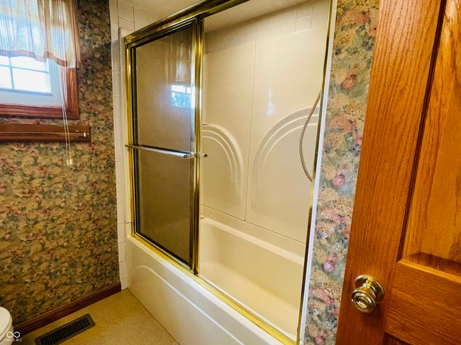 full bathroom featuring wallpapered walls, bath / shower combo with glass door, baseboards, and toilet | Image 17