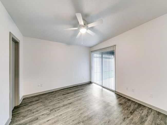 Empty room with wood finished floors, ceiling fan, and baseboards | Image 10