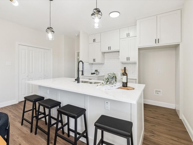 Kitchen featuring a sink, dark wood finished floors, baseboards, backsplash, and white cabinetry | Image 8
