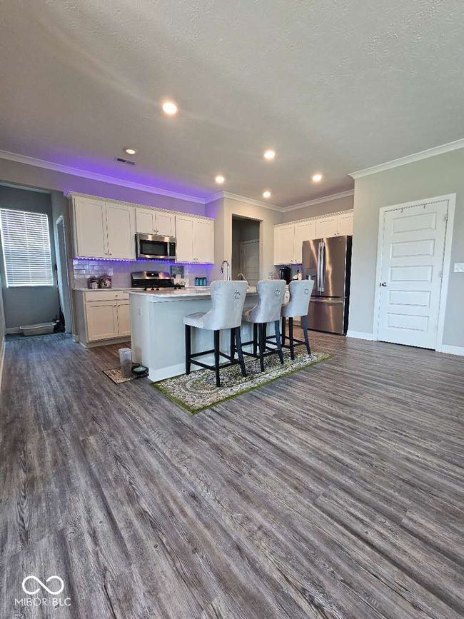 kitchen with stainless steel appliances, crown molding, dark wood-style floors, white cabinetry, and baseboards | Image 5