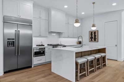 Kitchen with white cabinets, appliances with stainless steel finishes, pendant lighting, and a kitchen island with sink | Image 3