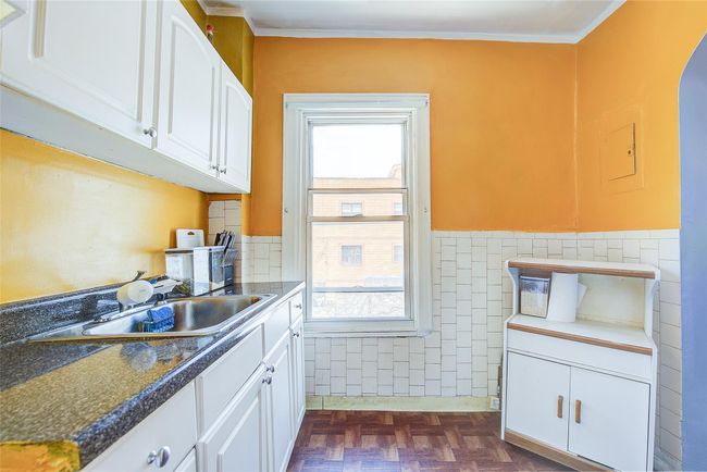 Kitchen featuring white cabinets, healthy amount of natural light, a wainscoted wall, tile walls, and dark countertops | Image 32
