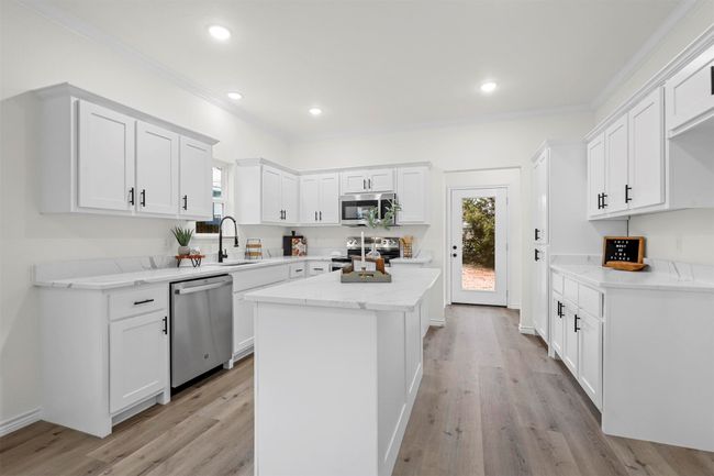 Kitchen with a kitchen island, sink, stainless steel appliances, and white cabinetry | Image 14