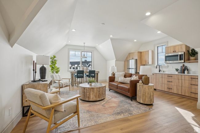 Living room with vaulted ceiling, baseboards, light wood-style flooring, and a healthy amount of sunlight | Image 35