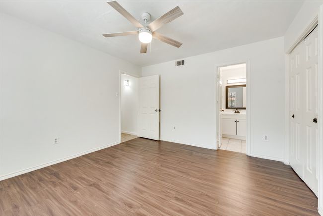Unfurnished bedroom featuring light wood-style flooring, a closet, connected bathroom, and a ceiling fan | Image 13