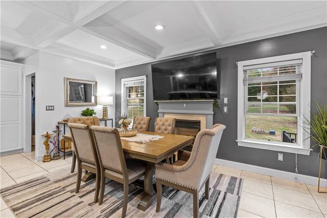 Dining space featuring light tile patterned floors, beamed ceiling, baseboards, a fireplace, and ornamental molding | Image 10