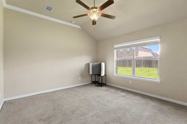 Carpeted empty room featuring vaulted ceiling, ceiling fan, and ornamental molding | Image 22