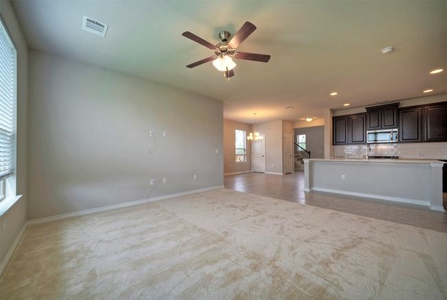 Unfurnished living room with recessed lighting, ceiling fan with notable chandelier, baseboards, visible vents, and light carpet | Image 13