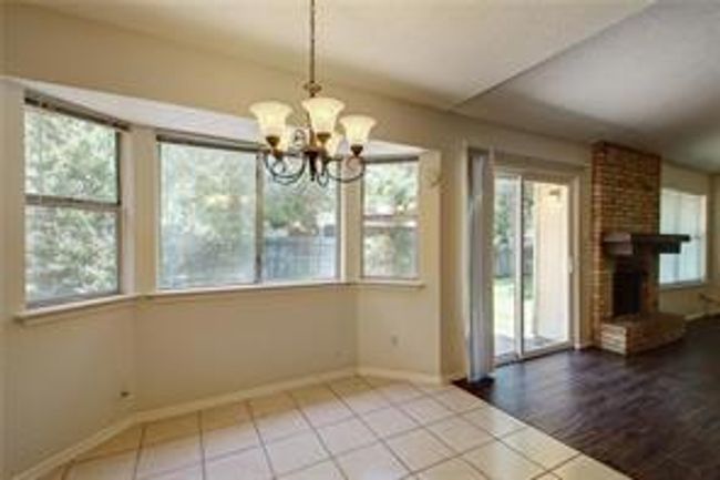 Unfurnished dining area featuring a chandelier, tile patterned flooring, a fireplace, and baseboards | Image 12
