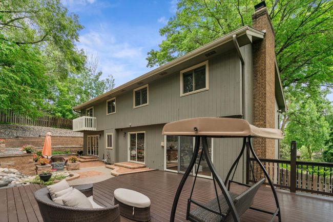 Stunning multi-level backyard retreat featuring an expansive freshly stained deck, built-in seating areas, lush landscaping, and walkout access from multiple sliding doors. | Image 28