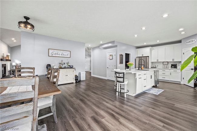Kitchen with an island with sink, dark wood-type flooring, backsplash, sink, and white cabinetry | Image 13