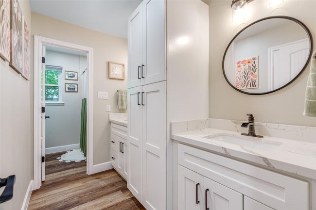 This stylish bathroom features a shower/tub combo, with the toilet thoughtfully separated from the dual white sink vanities, each complemented by custom framed mirrors for a sleek and functional design. | Image 14