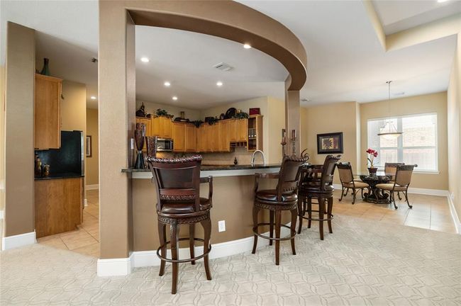 Charming, unique detailing can be found throughout the home, making everyday living feel like luxury. From the patterned carpet to the curved breakfast bar, gatherings in this space flow effortlessly into the sunny breakfast room, creating a warm, welcoming atmosphere for casual meals or morning coffee. | Image 8