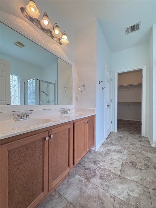 Full bath with a stall shower, double vanity, and a walk in closet | Image 16