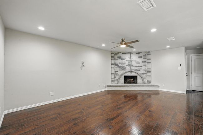 Unfurnished living room with a ceiling fan, wood finished floors, a fireplace, recessed lighting, and baseboards | Image 5