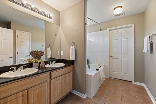 Bathroom featuring double vanity, tile patterned floors, baseboards, and tiled shower / bath combo | Image 20