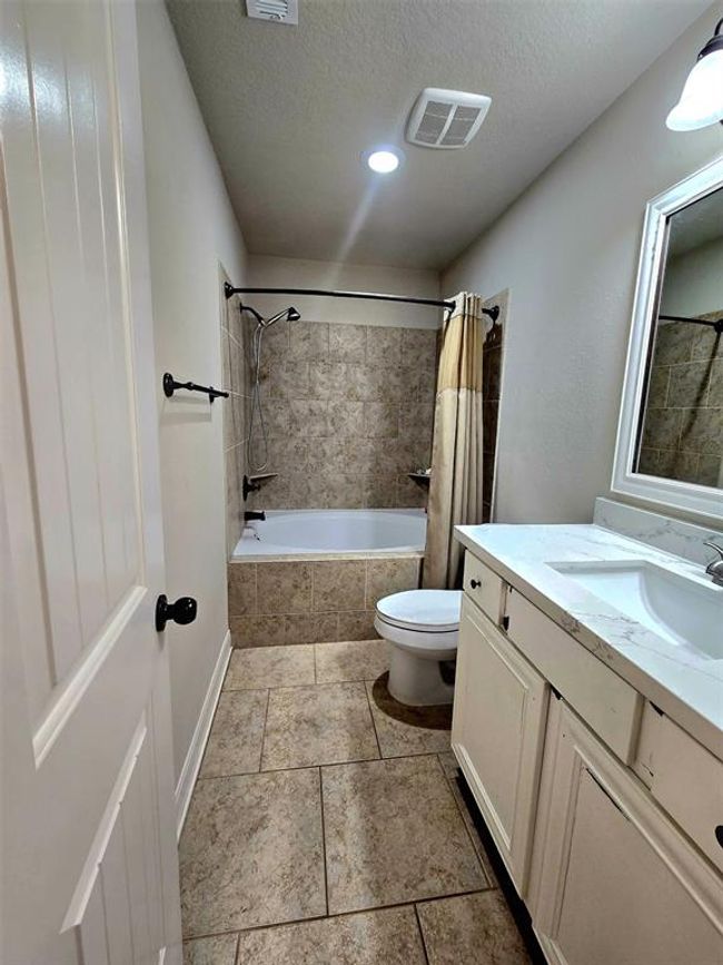 This bathroom features a tiled floor and shower area, a bathtub, a vanity with a sink, and a wall-mounted mirror. The neutral color palette and modern fixtures create a clean and inviting space. | Image 23