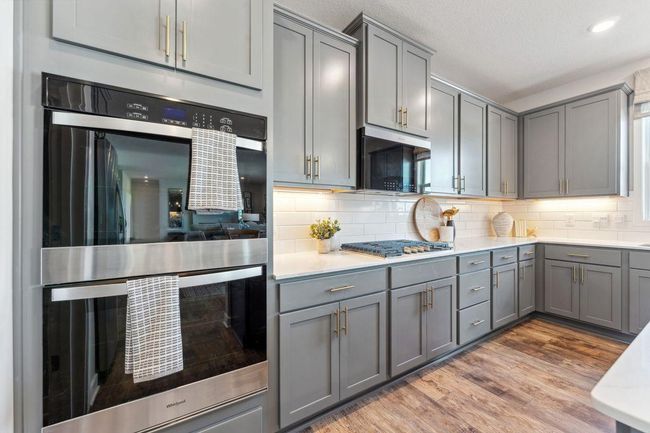 Your kitchen will include our KitchenAid Gourmet appliance package: a 5 burner gas cooktop, wood hood, built in microwave and convection oven, and dishwasher. Tiled backsplash included. Photo of model home, colors and finishes will vary. | Image 7