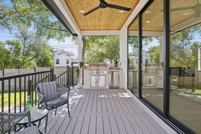 Wooden deck with an outdoor kitchen, area for grilling, a ceiling fan, and a fenced backyard | Image 29