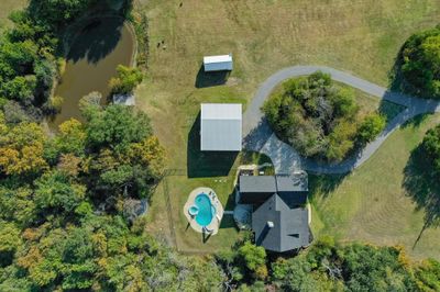 Overhead Aerial view of the circle drive up to the house, pool, shop, guest house and pond with fishing pier | Image 1