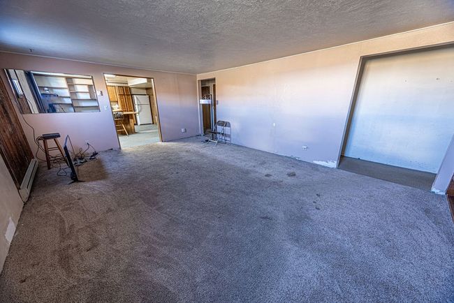 Unfurnished living room with a baseboard radiator, carpet, built in shelves, and a textured ceiling | Image 41