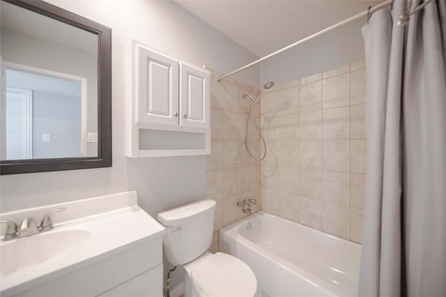 Full bathroom featuring shower / bathtub combination with curtain and vanity | Image 25