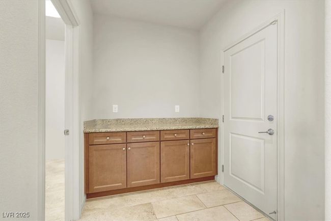 Kitchen featuring brown cabinets, light tile patterned flooring, and light stone countertops | Image 21