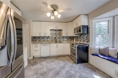 Kitchen with backsplash, sink, ceiling fan, appliances with stainless steel finishes, and white cabinets | Image 3