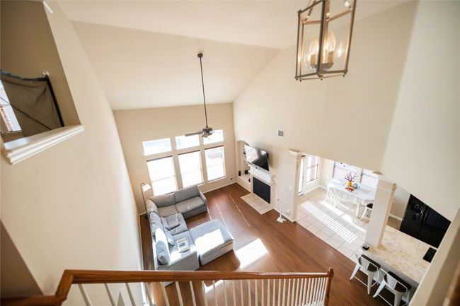 Living room with a ceiling fan, high vaulted ceiling, wood finished floors, and a fireplace with flush hearth | Image 37
