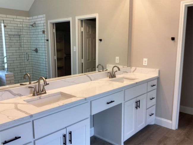 Bathroom featuring a shower stall, double vanity, wood finished floors, lofted ceiling, and a walk in closet | Image 19