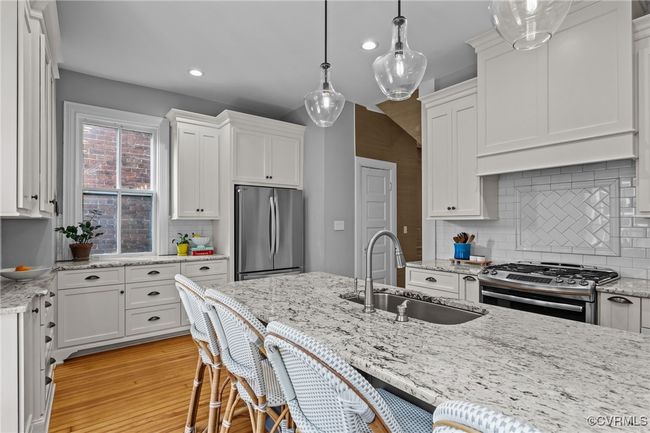 Kitchen featuring white cabinets, appliances with stainless steel finishes, decorative backsplash, and a sink | Image 14