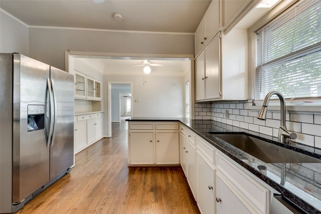 Kitchen featuring appliances with stainless steel finishes, a peninsula, a ceiling fan, backsplash, and ornamental molding | Image 13