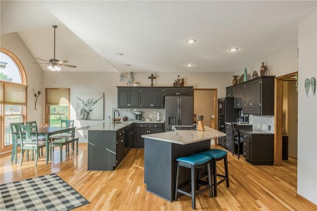 Kitchen with light wood finished floors, stainless steel fridge with ice dispenser, a peninsula, and a kitchen bar | Image 23
