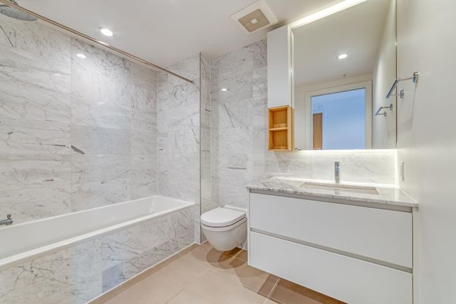 Full bathroom featuring toilet, a combined bath / shower with marble appearance, visible vents, vanity, and tile walls | Image 10