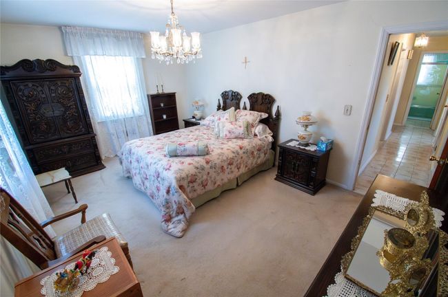 Bedroom featuring light colored carpet, baseboards, and a notable chandelier | Image 15