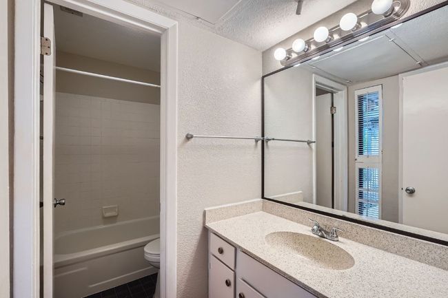 Full bath with a textured ceiling, toilet, vanity, shower / washtub combination, and a textured wall | Image 10