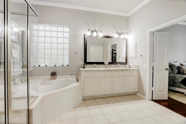This is a spacious and bright en-suite bathroom feature ample storage within the double vanity, linen shelves in the water closet and large closet. | Image 21