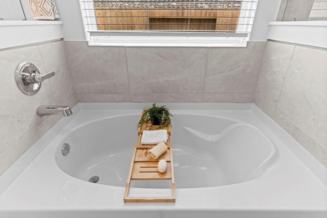 A closer look at the soaking tub reveals beautiful tilework, a picture window for natural light, and space to unwind in style. **Image Representative of Plan Only and May Vary as Built**. | Image 23