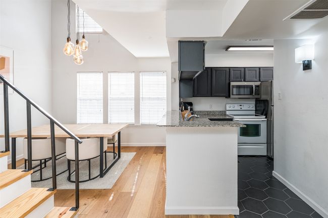 Kitchen featuring stainless steel microwave, electric stove, a peninsula, baseboards, and light stone countertops | Image 5