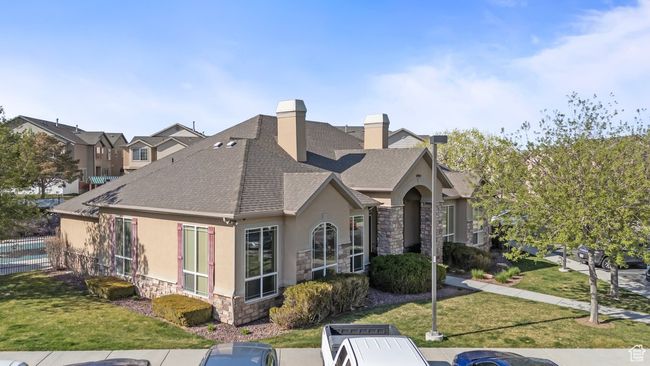 View of side of property featuring a yard, stucco siding, stone siding, a chimney, and a shingled roof | Image 16