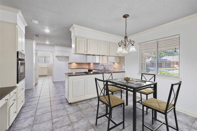 Dining space with crown molding, baseboards, light tile patterned floors, a textured ceiling, and a chandelier | Image 7