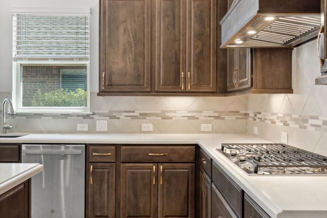 Kitchen featuring dark brown cabinetry, a sink, stainless steel appliances, and exhaust hood | Image 18